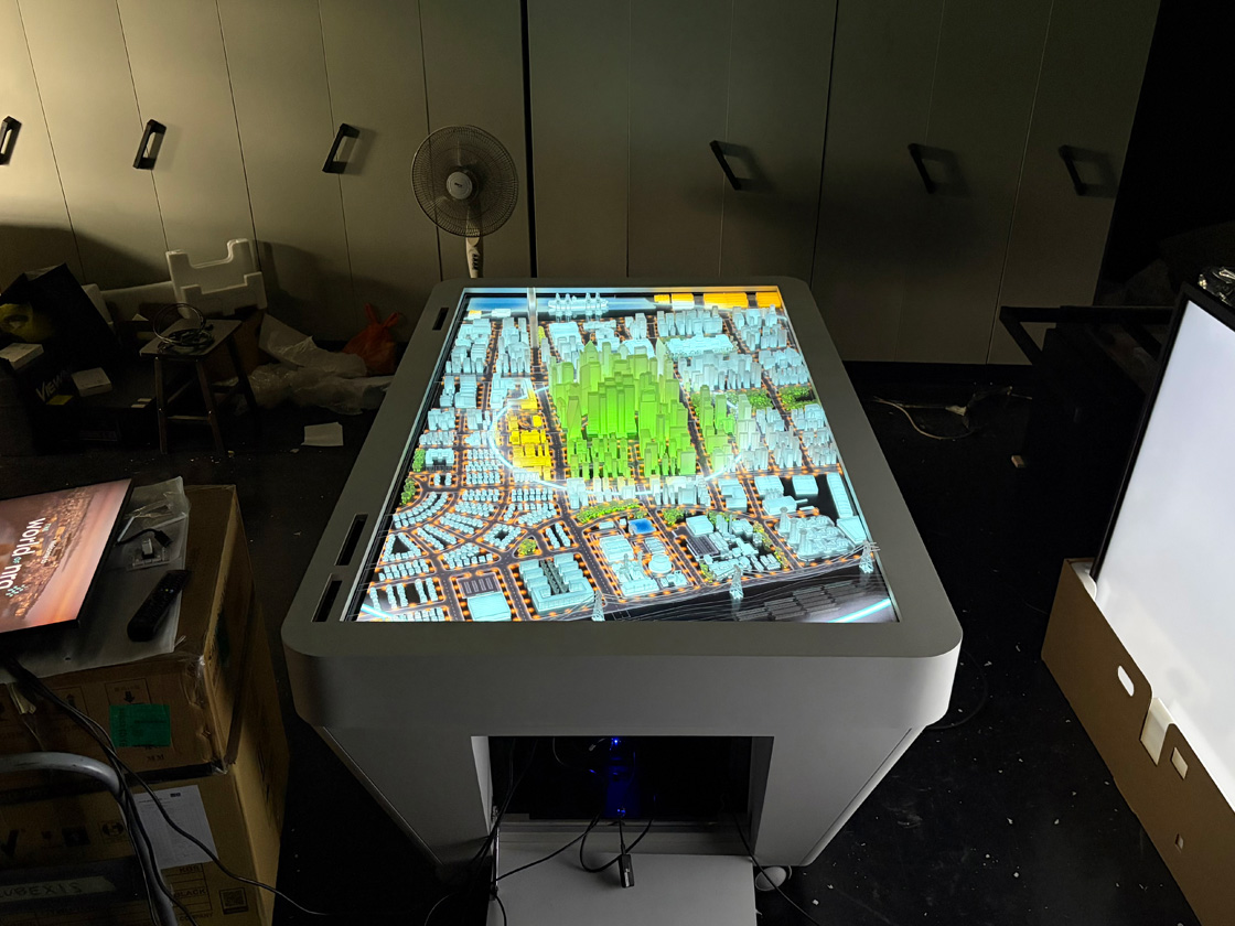 The 3D-printed city lit from below by the screen during assembly in the workshop