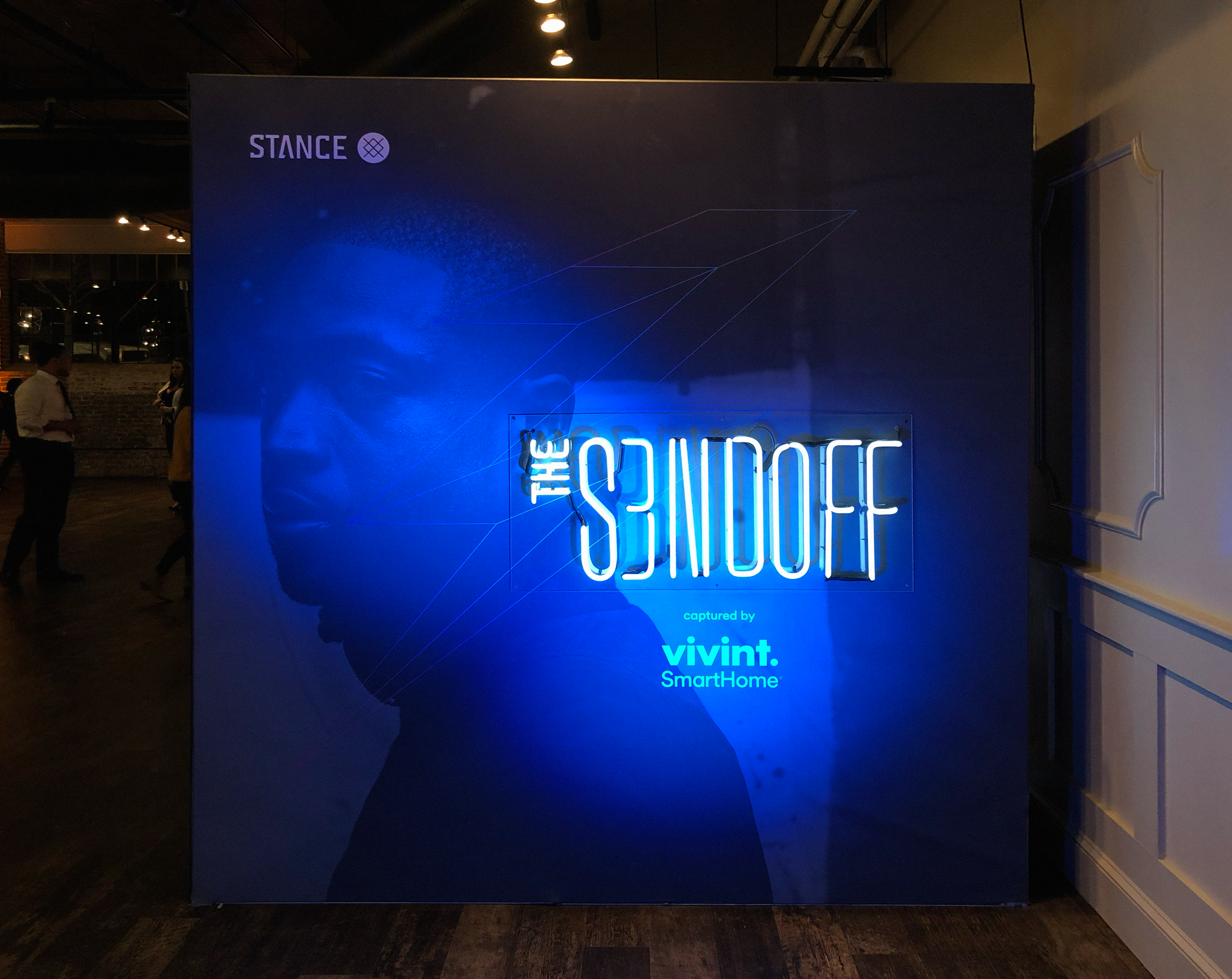 Blue-lit S3NDOFF backdrop with a neon sign and the Stance and Vivint logos